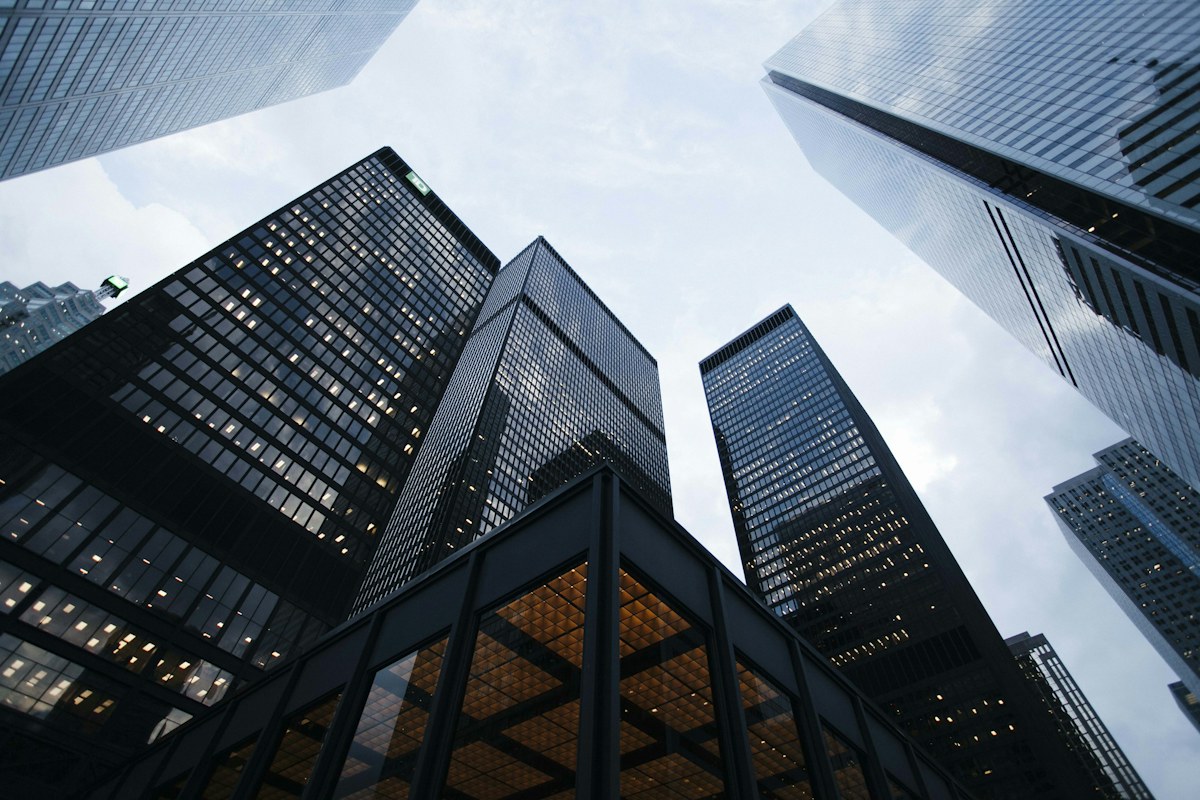 Glass-and-steel office towers viewed from below, representing modern engineering workplaces and global capability centers.