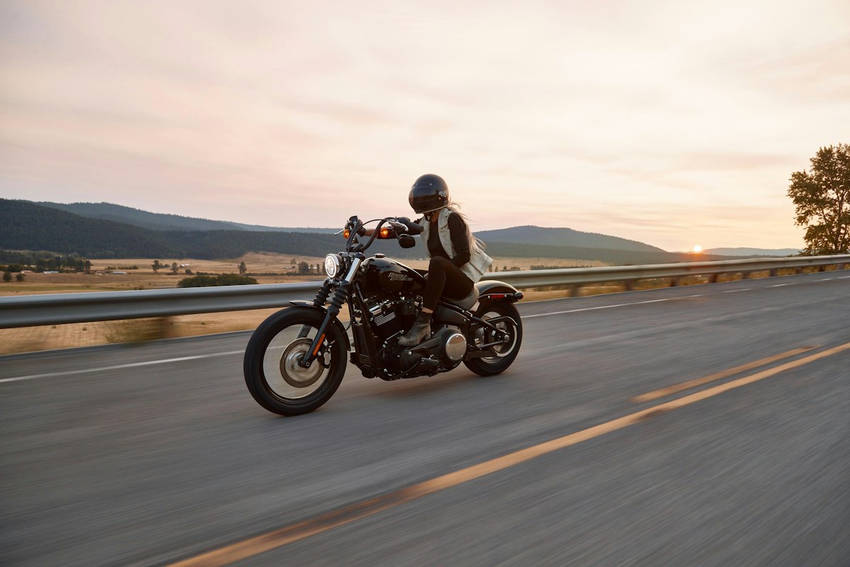 A motorcyclist travels along an open road during the evening.