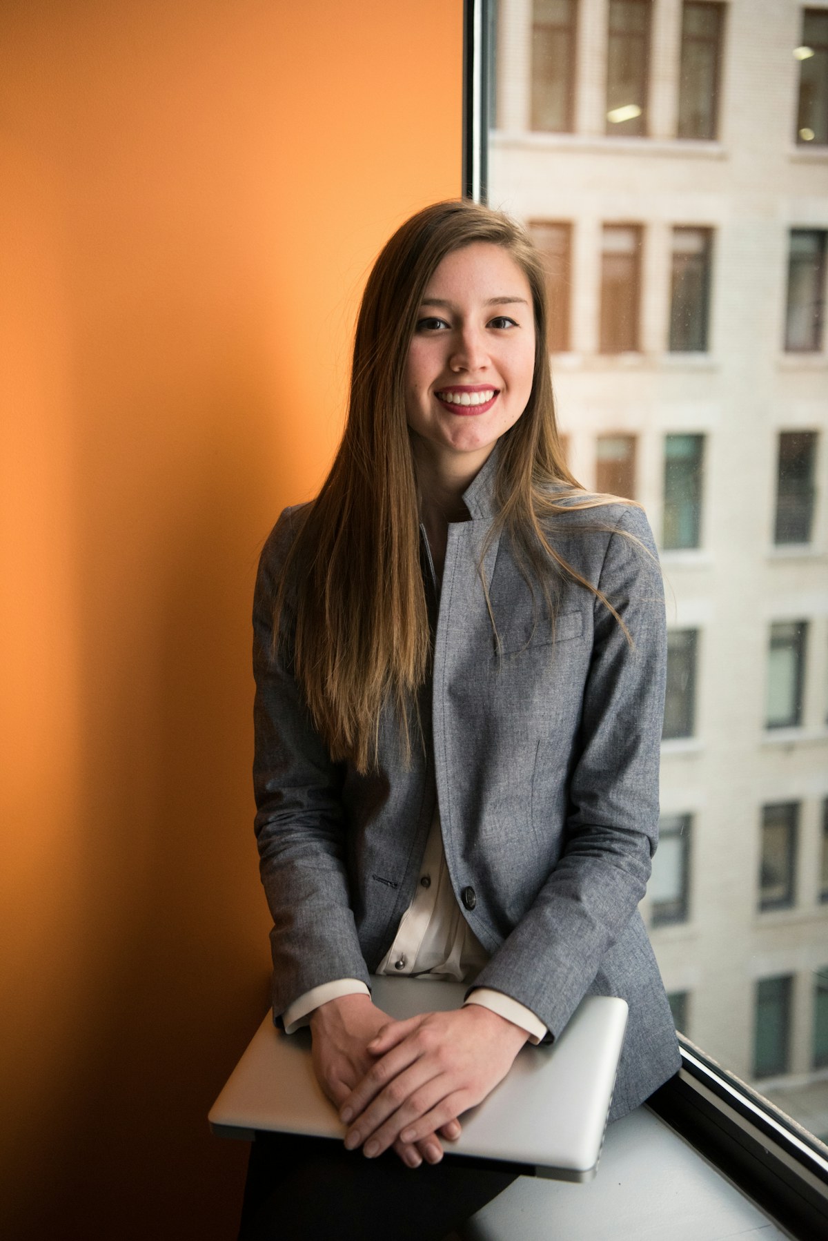 A woman sits for a professional portrait in a modern office.