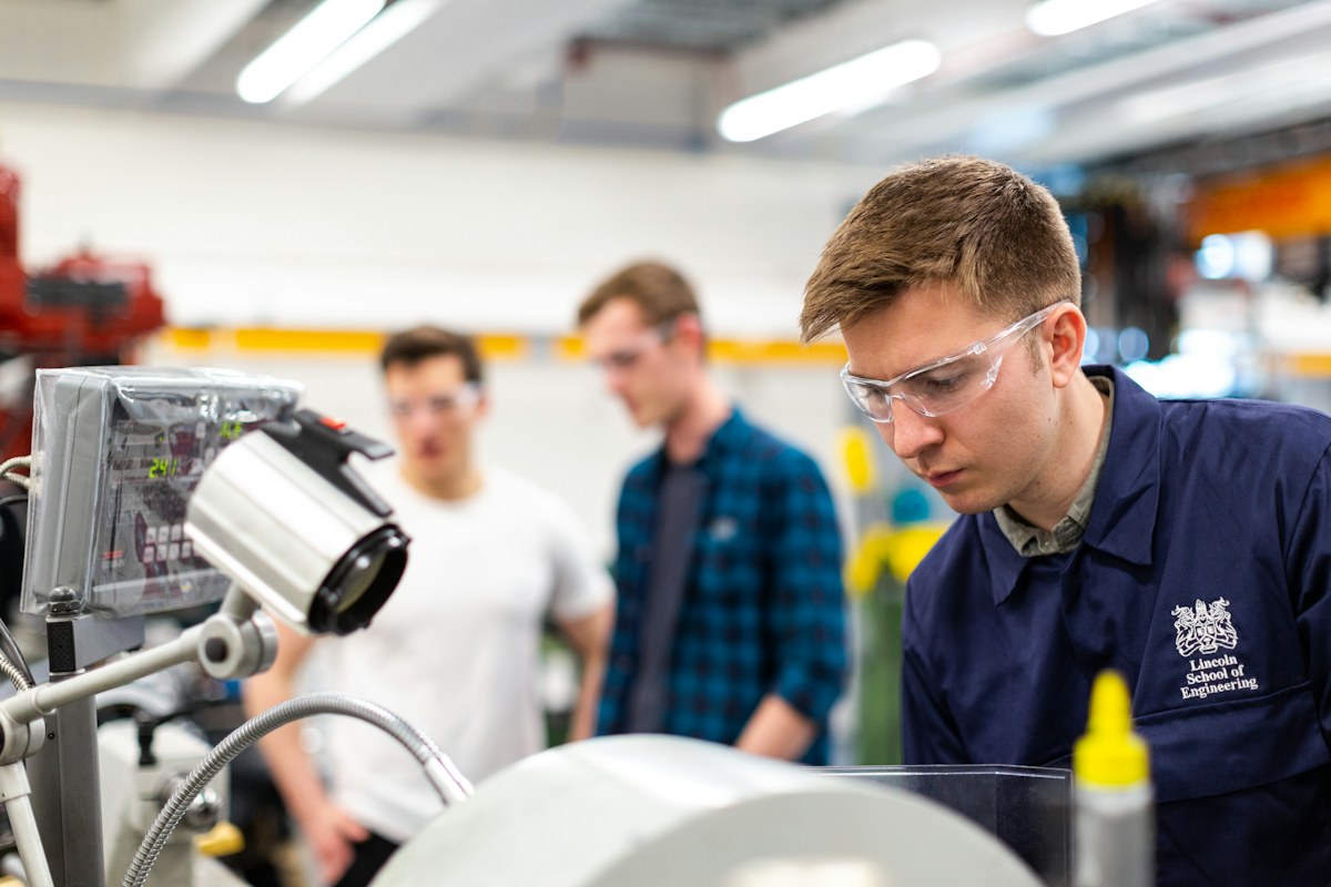 A manufacturing engineer examines a small component on a production floor.
