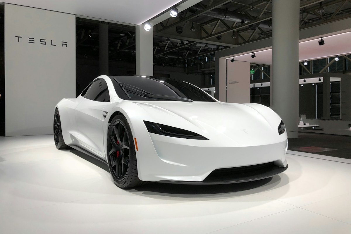 A white electric car is shown in a modern engineering or testing studio.